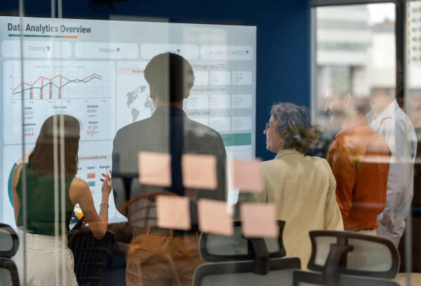 Diverse business development team brainstorming new products and services using a digital display during a business meeting. Business Intelligence and data-driven decisions empowering strategy, growth, and resilience in a modern office. Collaboration and innovation in action.