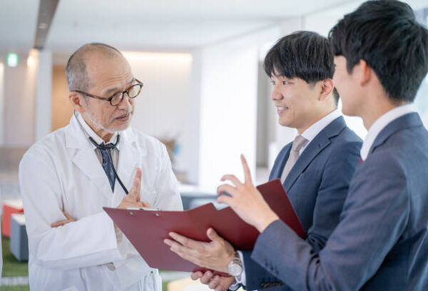 A male doctor and a medical information representative MR talk with smiles at the hospital.