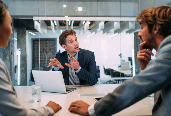 Shot of young couple having a consultation with a financial advisor in the office. Group of business persons in business meeting. Three entrepreneurs on meeting in board room. Corporate business team on meeting in modern office. Male manager discussing new project with his colleagues. Company owner on a meeting with two of his employees in his office.