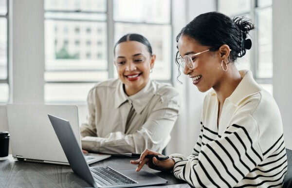 Business women, laptop and and happy team in office  for web design, collaboration and training. Planning, digital marketing and coaching by woman leader menor help, explain and support creative goal