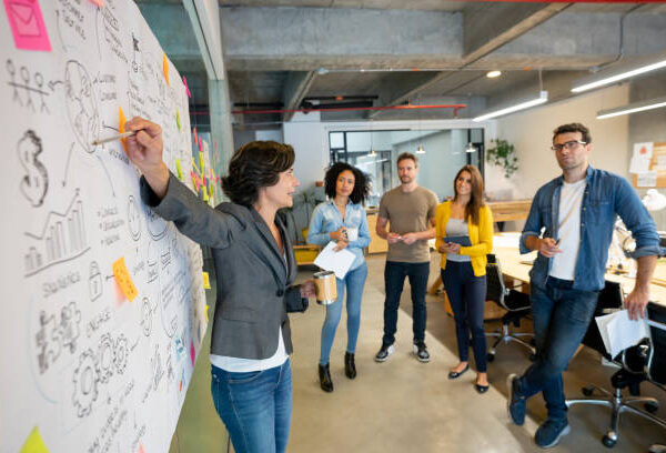 Latin American woman making a business presentation in a meeting at a creative office and pointing to her team her business plan