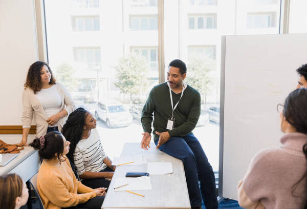 The professor provides feedback to a group of students in his classroom.