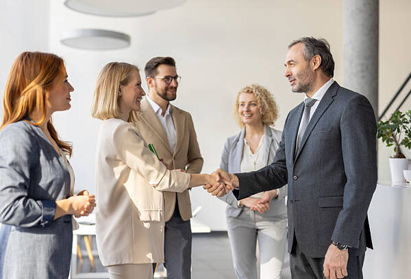 A professional meeting with business people shaking hands happily in a bright and modern office environment, showcasing collaboration and success.