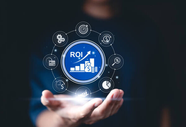 ROI - Return on Investment analysis concept. A hand holds digital interface showing ROI metrics, with icons for financial growth, strategy, performance analysis, investment efficiency, profitability,